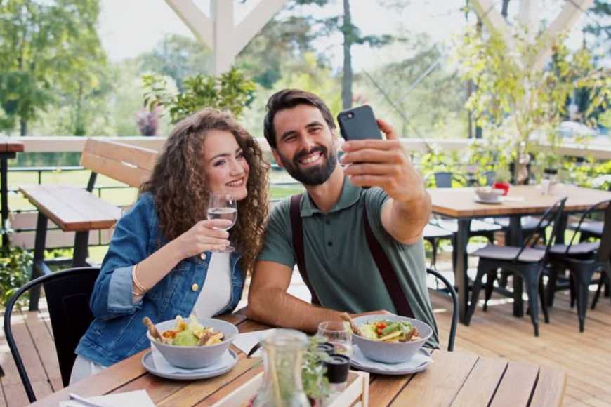 a_couple-taking_selfie_in_an_outdoor_restaurant